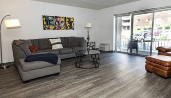 an open living room with a couch and chair and a sliding glass door leading to a balcony